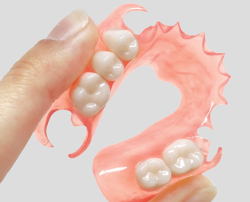 A flexible partial denture held between the fingers